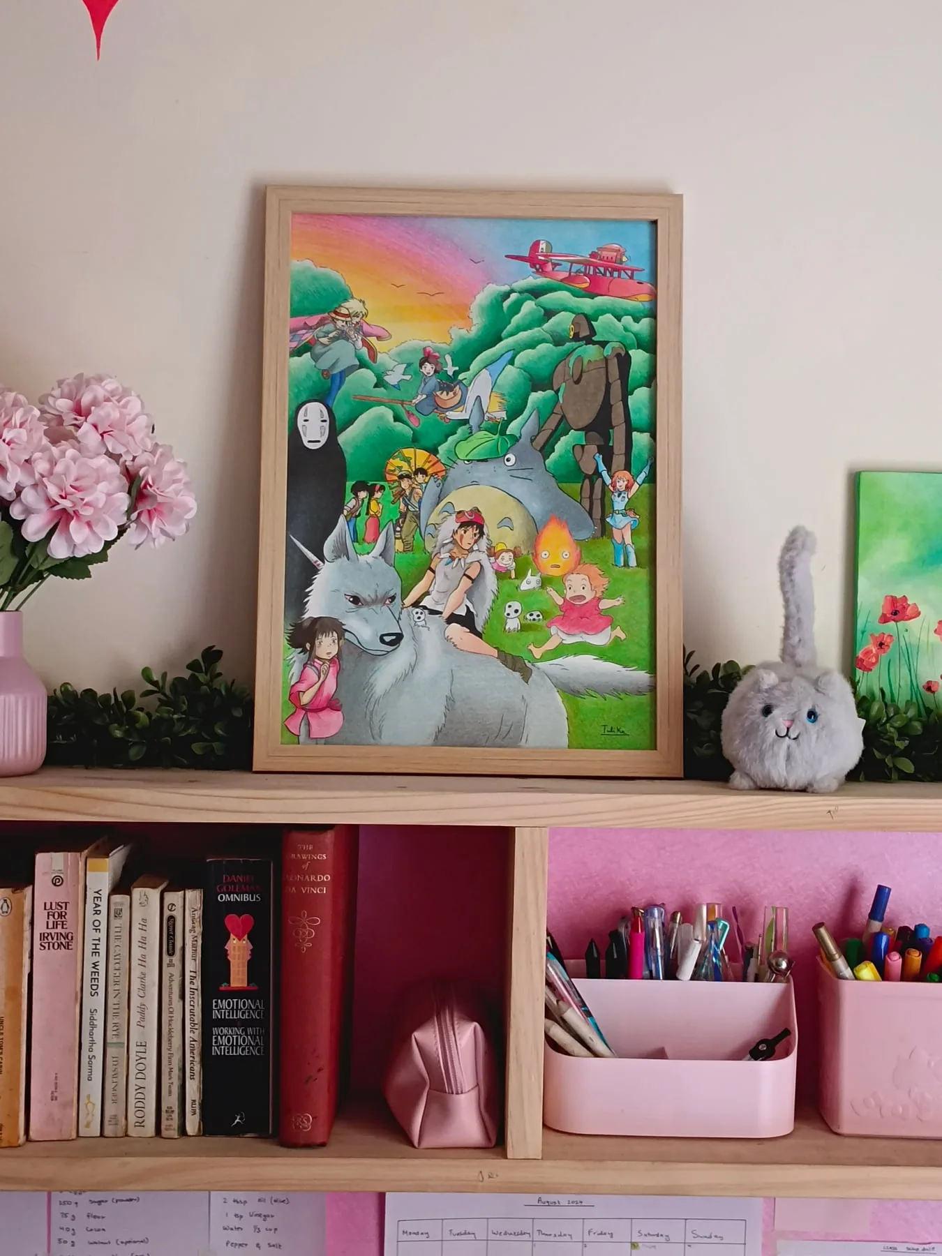 Framed colour-pencil fantasy landscape with Studio Ghibli-style characters, displayed on a shelf.
