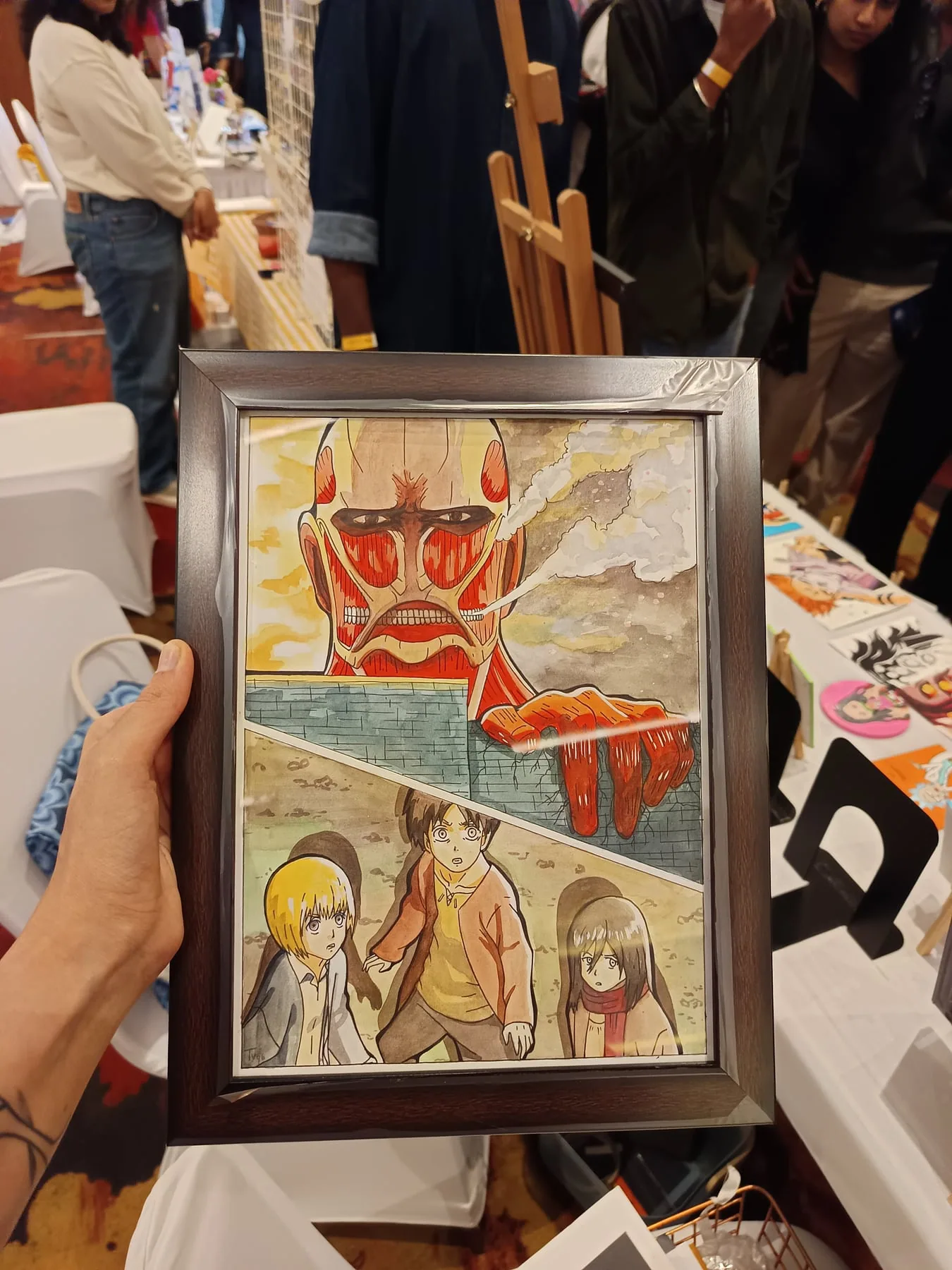 Framed hand-painted Attack on Titan scene featuring the Colossal Titan and Survey Corps characters, held at an art table.