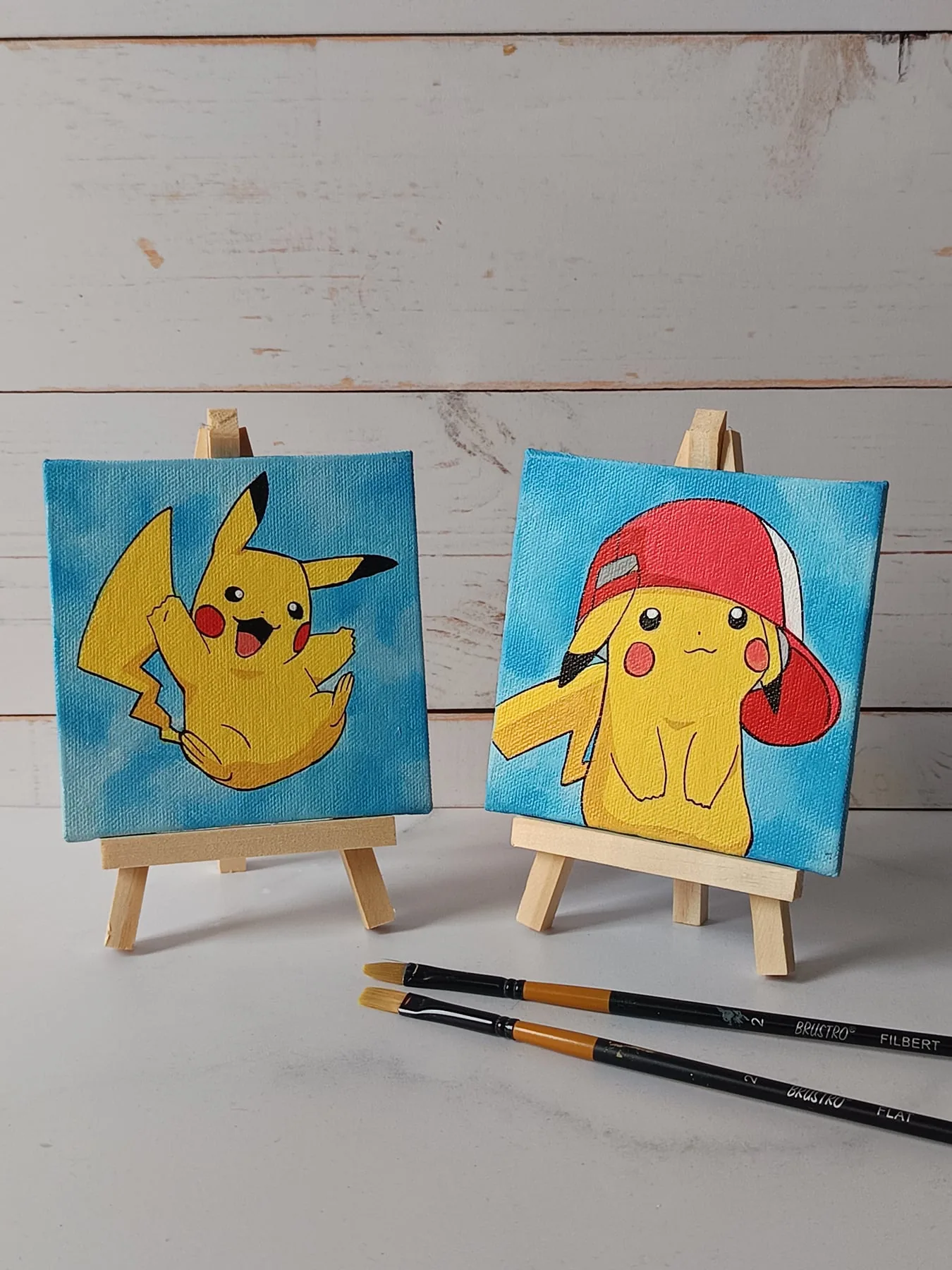 Pair of hand-painted acrylic mini canvases featuring Pikachu from Pokemon, displayed on small easels.