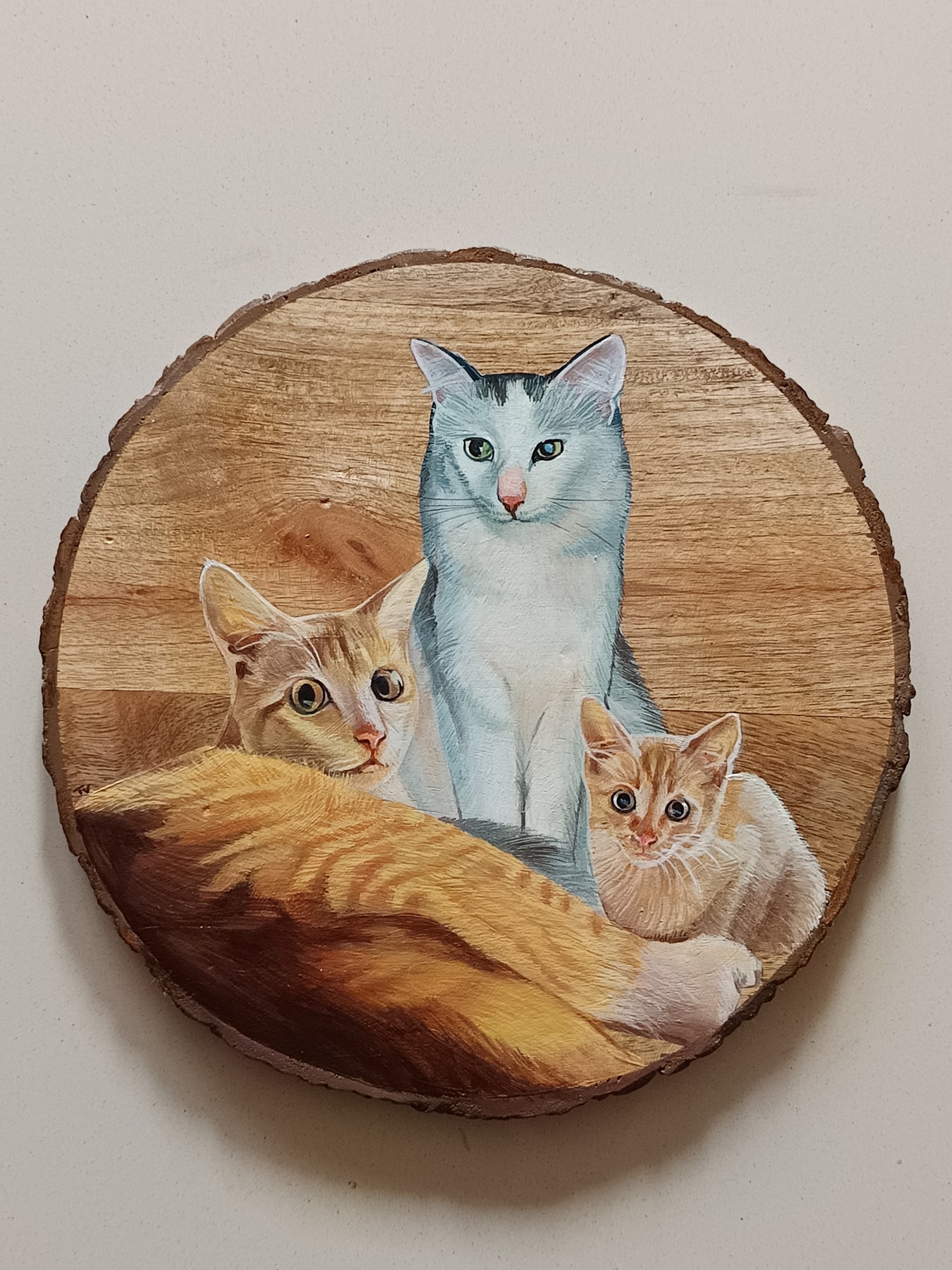 Three cats painted on a round wood slice