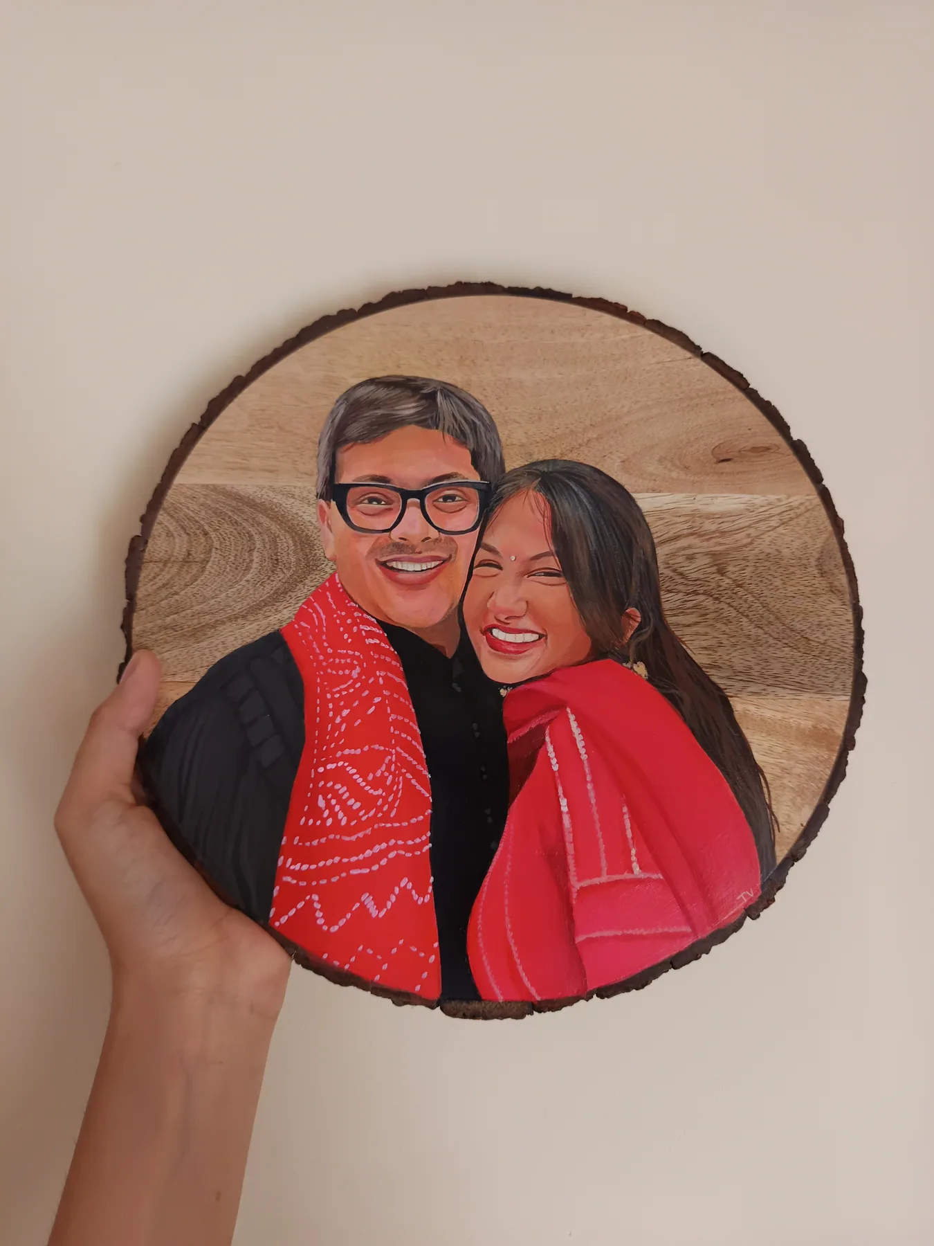 Round wood slice couple portrait of two smiling people in red scarves, held in hand as a personalised gift.
